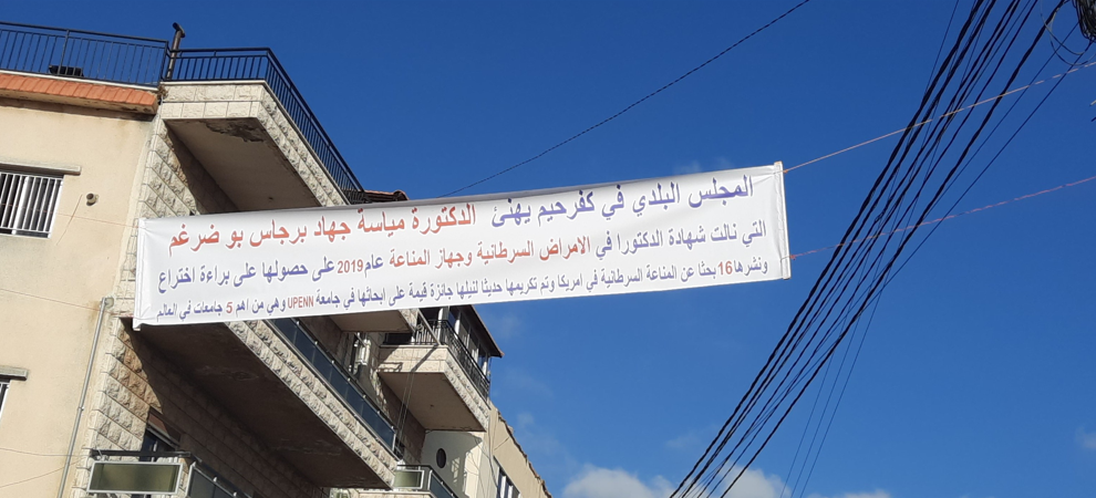 A banner hanging across a building, honoring the academic achievements of Mayassa Bou-Dargham, in her Lebanese hometown